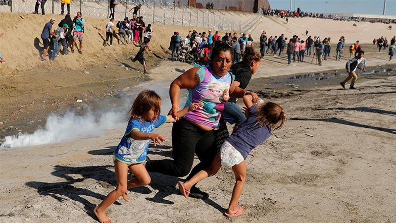A woman and what appear to be her children flee from the tear gas attack at the border