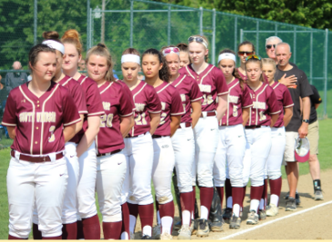 The Varsity Softball team lines up on the 3rd base line for the National Anthem