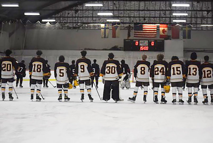 South Windsor boys hockey players lined up with helmets off on the ice for the National Anthem.