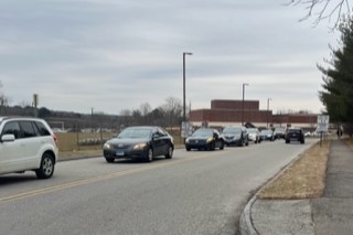 Cars line up to escape the school after navigating through the traffic when school ends.