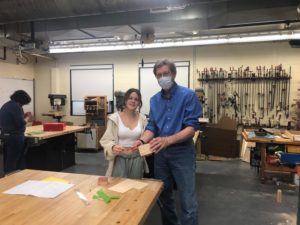 Dr. Raymond Macarthy helping a student with their woodworking project using a rough draft sketch. 
