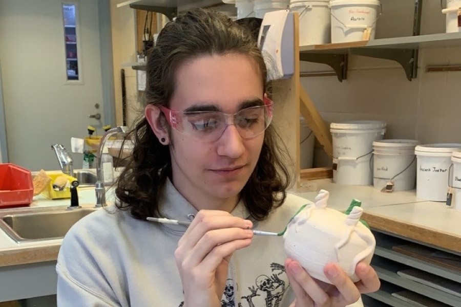 Senior making finishing touches on his artwork in his 2nd period pottery class. 