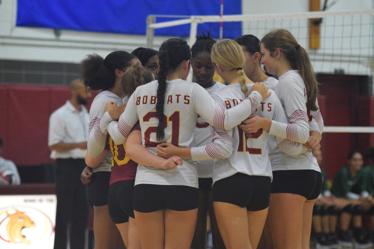 The South Windsor Varsity Girls Volleyball team huddles around one another after a point.
