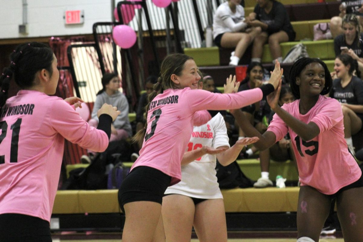 The South Windsor High School varsity volleyball players congratulate one another on a successful play.