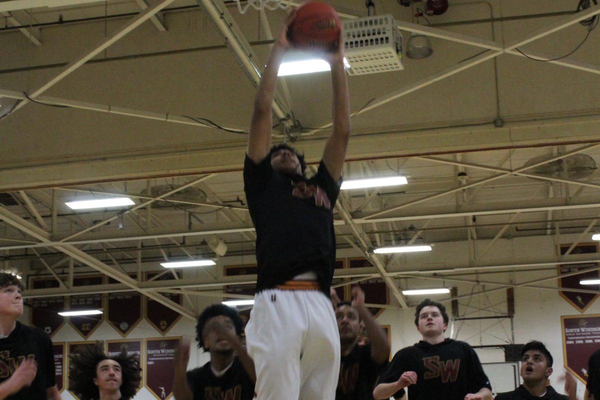 Junior Tyler Pottinger warms up with his teammates behind him.