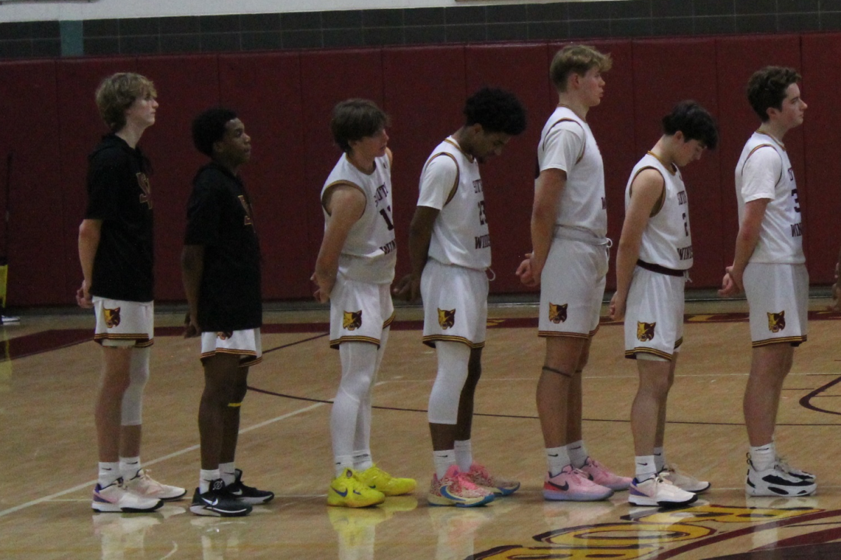 The boys basketball starting line up standing for the National Anthem. 