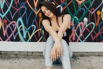 Victoria Tori Brindis posing in front a painting on the sidewalks of California.