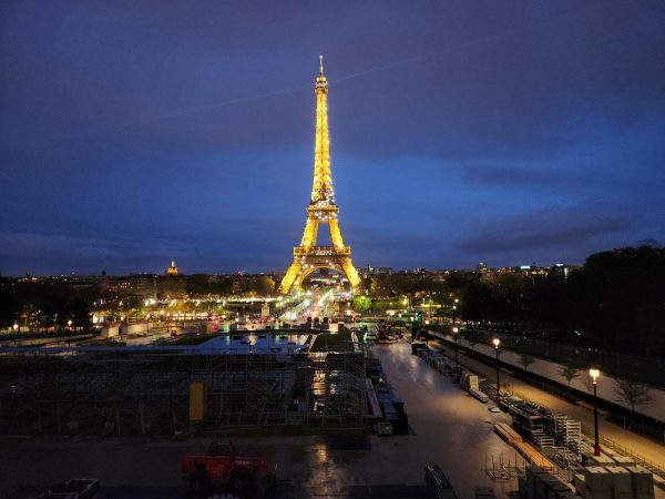 The Effiel Tower lights up after sunset, as students look on