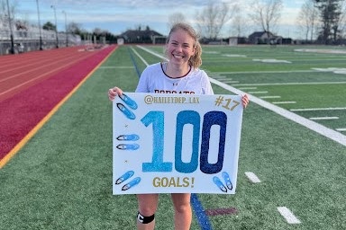 Hailey Deptula holds a sign made in celebration of her 100th goal.
