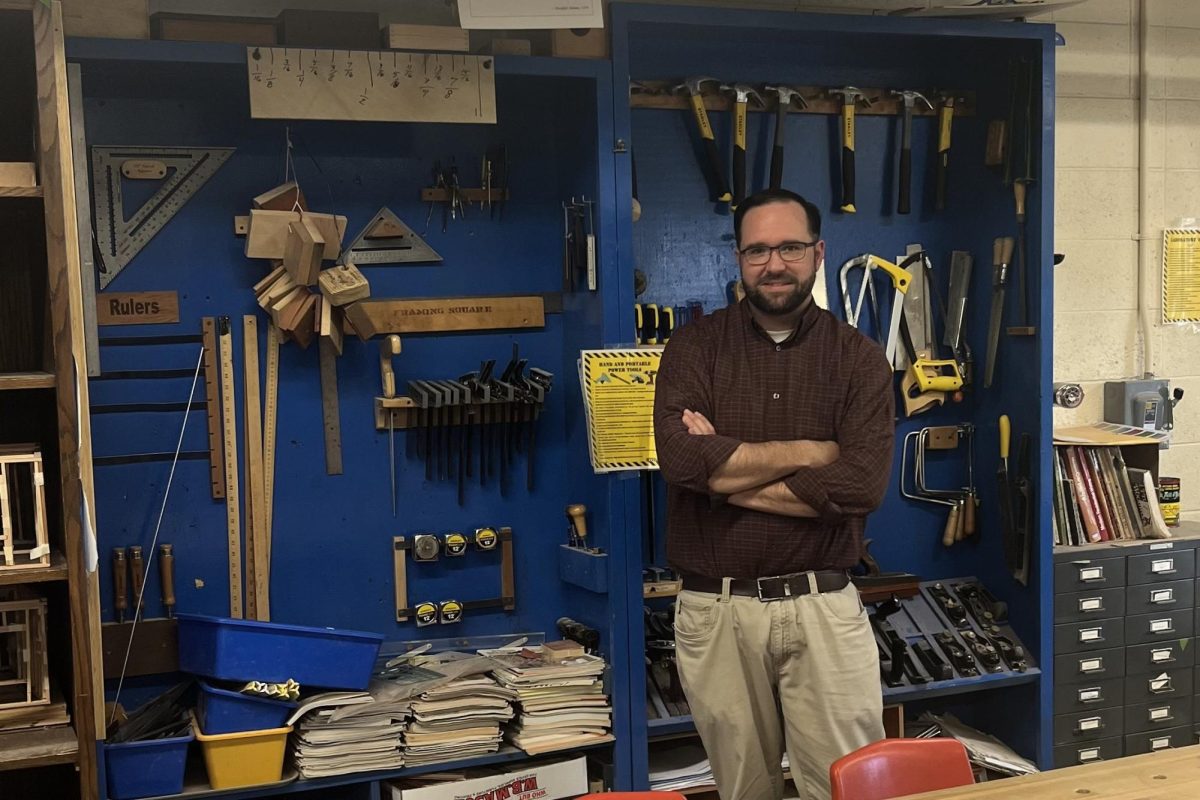 Tech+education+teacher+and+Bobcat+Nation+News+advisor+in+front+of+the+tool+wall+in+the+woodworking+classroom.