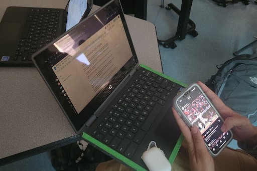 A student using their cell phone to scroll on Instagram during one of their classes.
