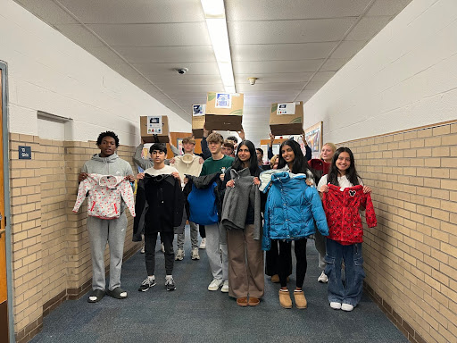 Students from Mrs. Barrett's period 4 Marketing class holding coats from the coat drive.