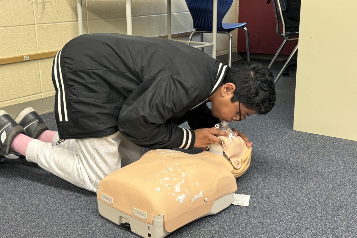 Senior Vaibhav Tirunagari performing ventilations on an adult mannequin after a round of CPR.