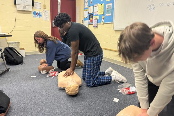  Three students practice single CPR on adult mannequins in class. 