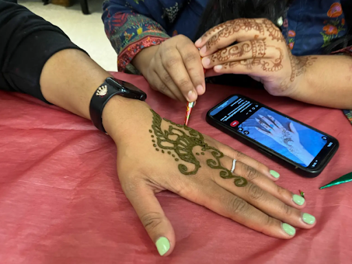 A skilled Henna artist draws a design on a person's hand during the Holi celebration at SWHS. 