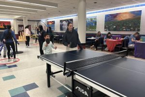 Junior Samantha Roux plays ping pong with one of the kids.