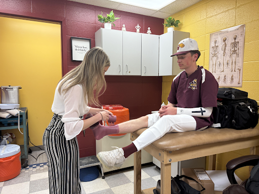 Athletic trainer Sara Robinson wraps a player's ankle before a game.