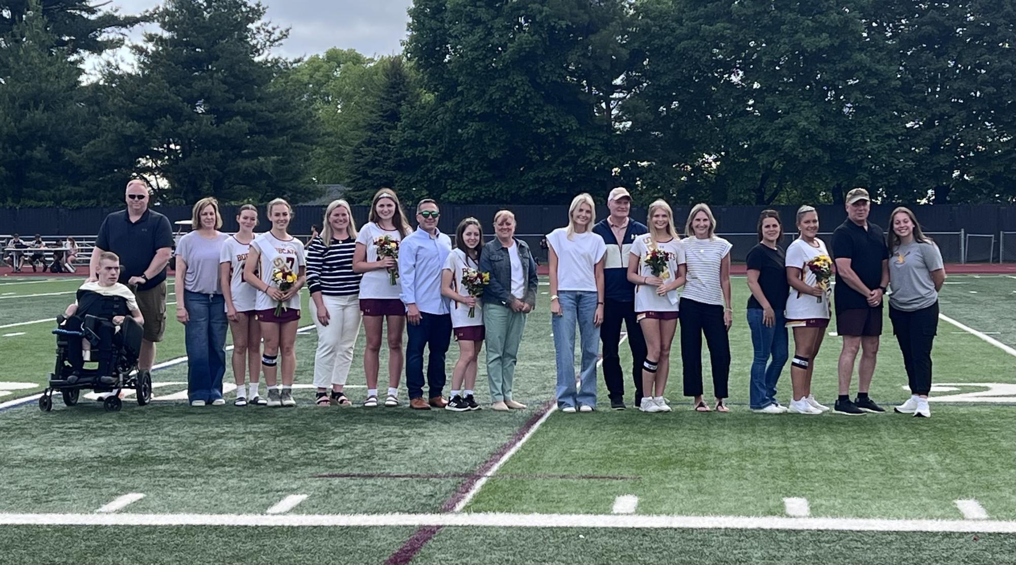 Seniors pose for a photo with their parents on the field during Senior Night.