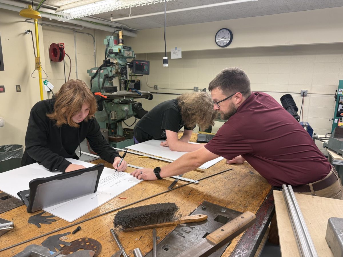 A teacher is engaged in helping with a student’s work, exemplifying one of the qualities of the Portrait of an Educator