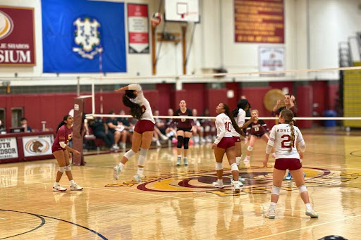 Senior Captain Ioana Luangpraseuth hitting the ball while her team covers her.