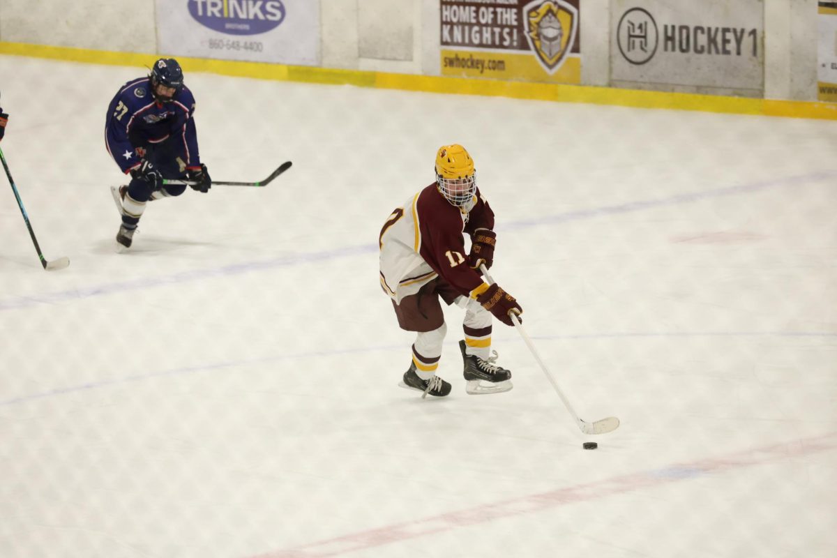 South Windsor sophomore Gavin Plunske skates up the ice with the puck against Newtown.