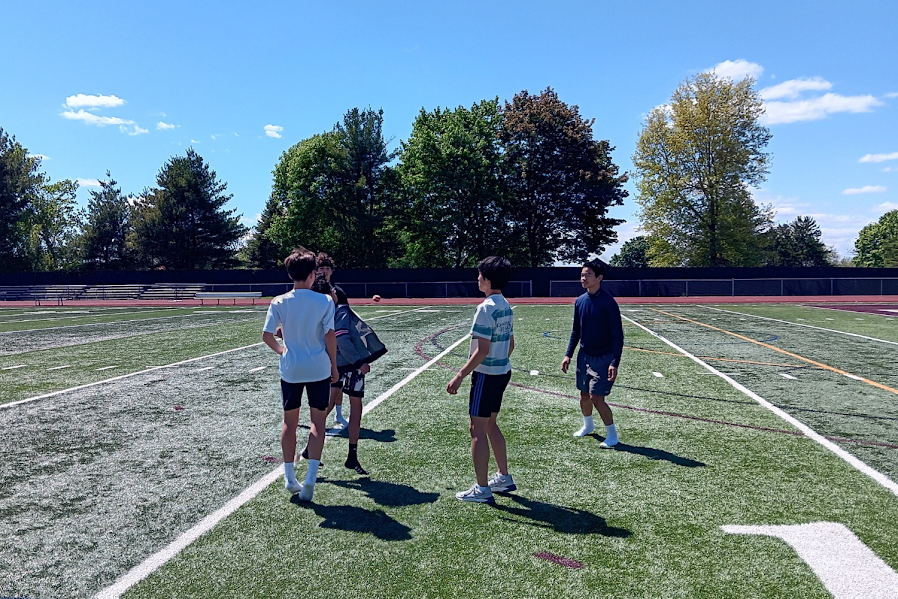 Several students of all ages playing Hacky Sack before the start of Track practice.